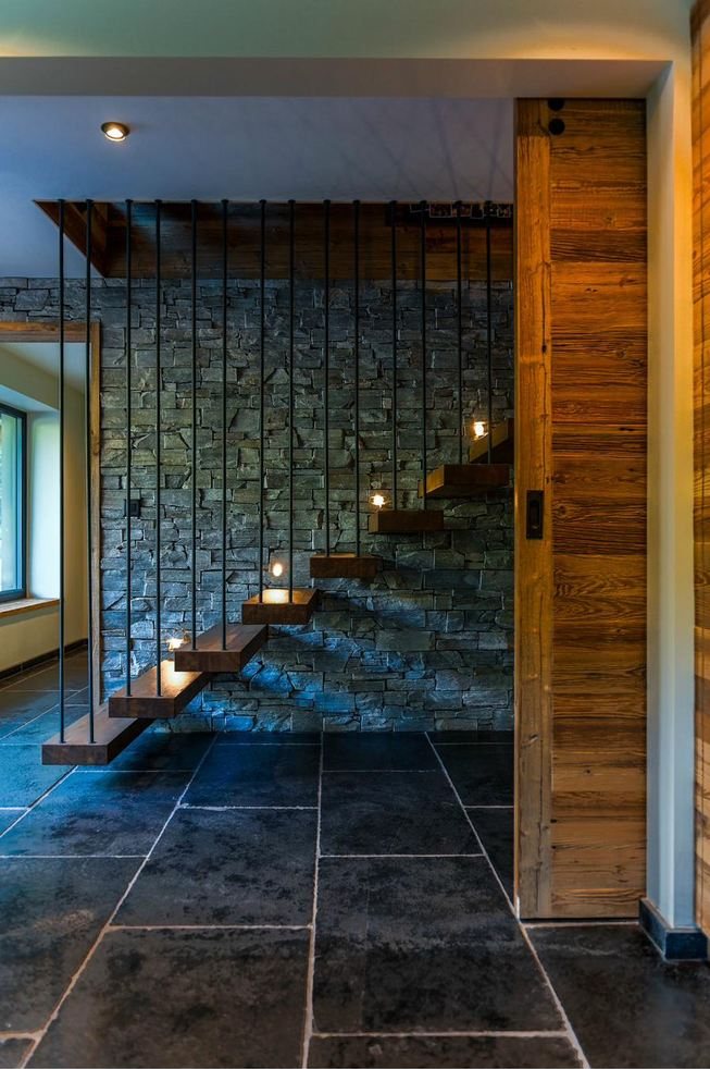 The finished floating staircase against the stone wall